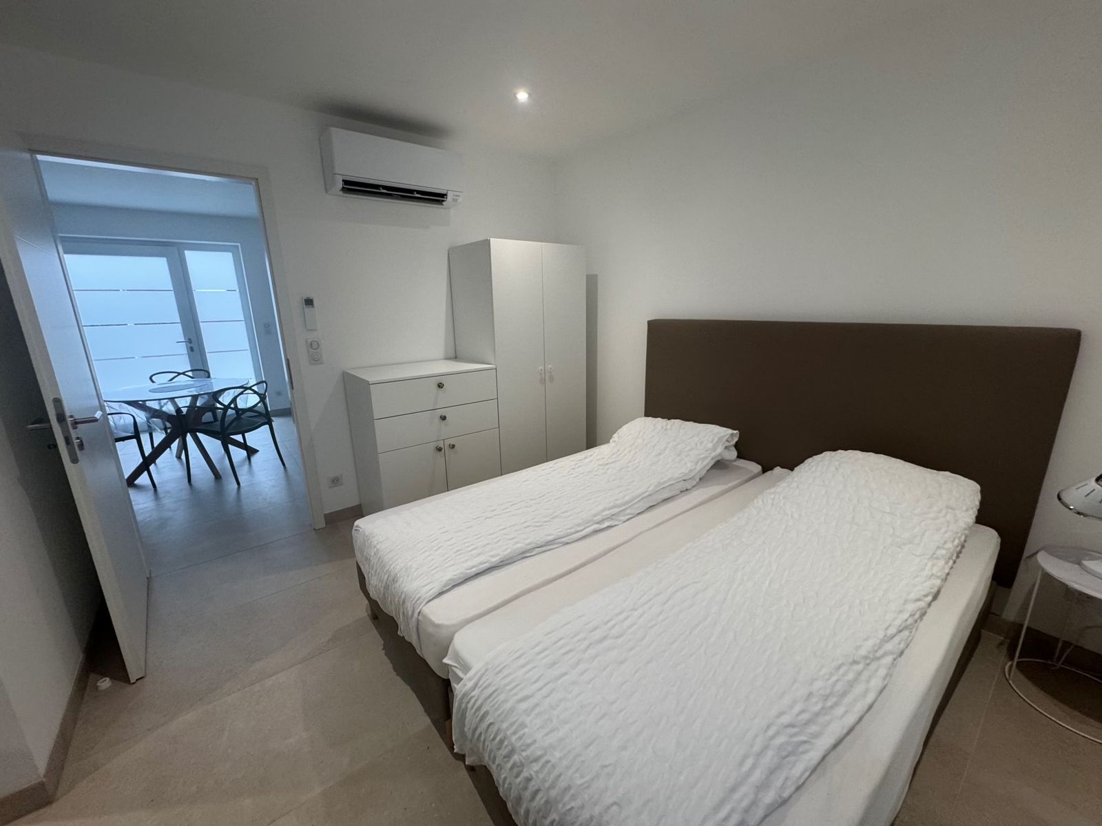 Chambre avec lits, armoire, commode et climatisation murale